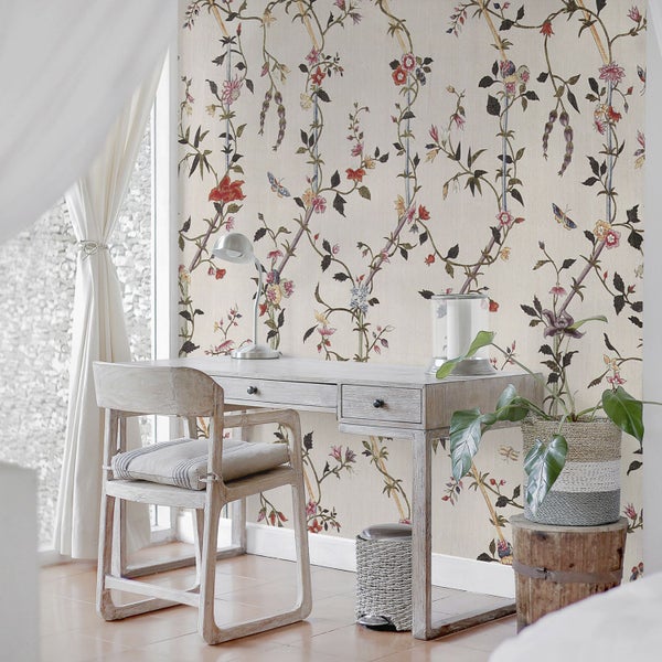 Szene mit Schreibtisch, Stuhl und floraler Tapete in einem hellen Raum