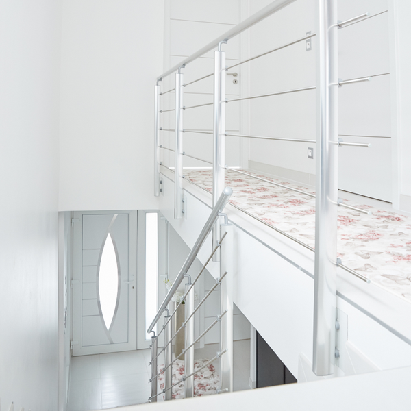 Heller Flur mit Treppe, Edelstahlgeländer und Teppich