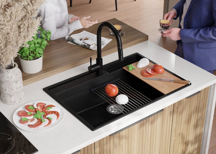 Schwarze Spüle mit Abtropfgitter, Schneidebrett, Armatur und Zutaten für Caprese in einer modernen Küche.