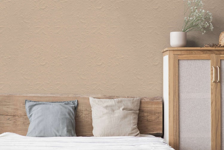 Strukturierte Tapete in Beige im Schlafzimmer hinter einem Bett mit Kopfteil aus Holz und einem Holzschrank.