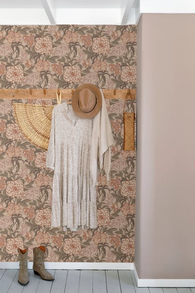 Dekoratives Zimmer mit Blumentapete, Kleiderhakenleiste, Kleid, Hut, Strickjacke, Strohtasche und Cowboystiefeln