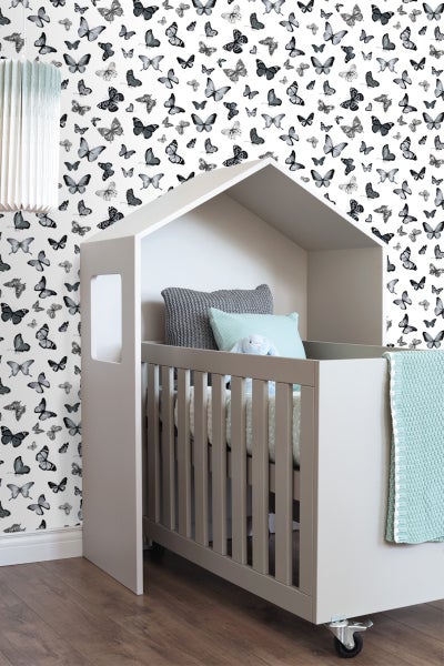 Kinderzimmer mit Kinderbett in Hausform vor Tapete mit Schmetterlingsmotiv