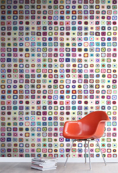 Wand mit Tapete im Patchwork-Design, ein Sessel und ein Stapel Zeitschriften