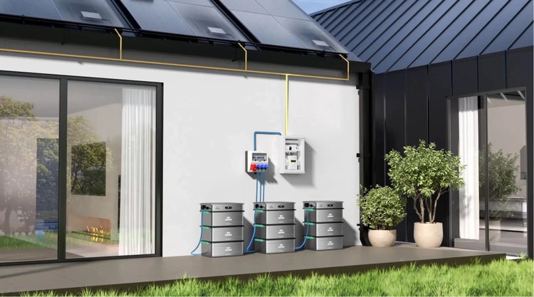 Modernes Haus mit Solaranlage auf dem Dach, drei Batteriespeichern mit Zendure Logo auf der Terrasse und Steuerungseinheiten an der Außenwand.