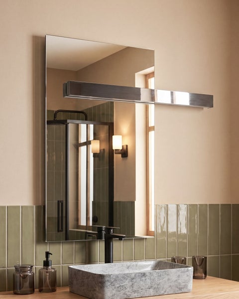 Modernes Badezimmer mit Spiegel, horizontaler Spiegelleuchte aus Chrom, Aufsatzwaschbecken in Natursteinoptik und einer schwarzen Armatur.