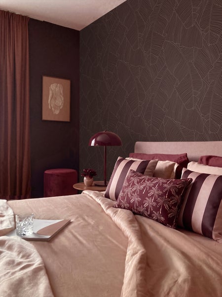 Wohnzimmer mit brauner Blättertapete, Sessel und Schrank
