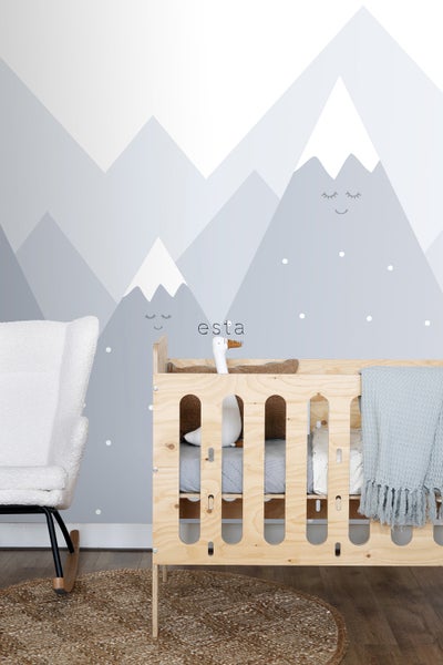 Kinderzimmer mit Holzbett, Schaukelstuhl und Bergtapete