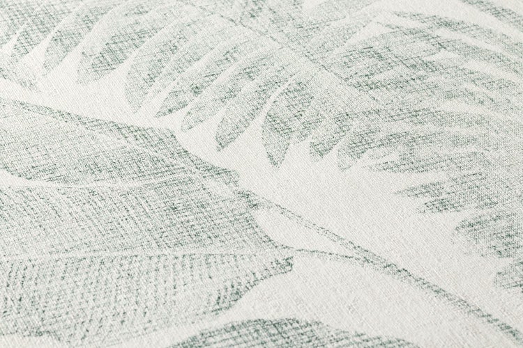 Detailansicht eines Rattanmöbels mit Kissen vor einer Wandtapete mit Blattmuster.