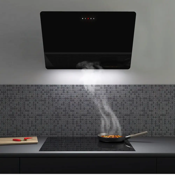 Schwarze, schräg an der Wand montierte Dunstabzugshaube mit Beleuchtung über einem Induktionskochfeld und einer Pfanne mit aufsteigendem Dampf.