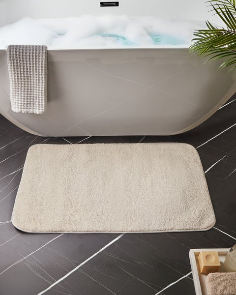 Badewanne mit Badeschaum, Badematte und Handtuch in einem Badezimmer
