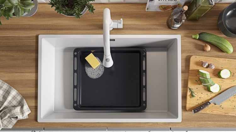 Küchenspüle mit Geschirr und Zutaten für die Essenszubereitung auf der Arbeitsfläche