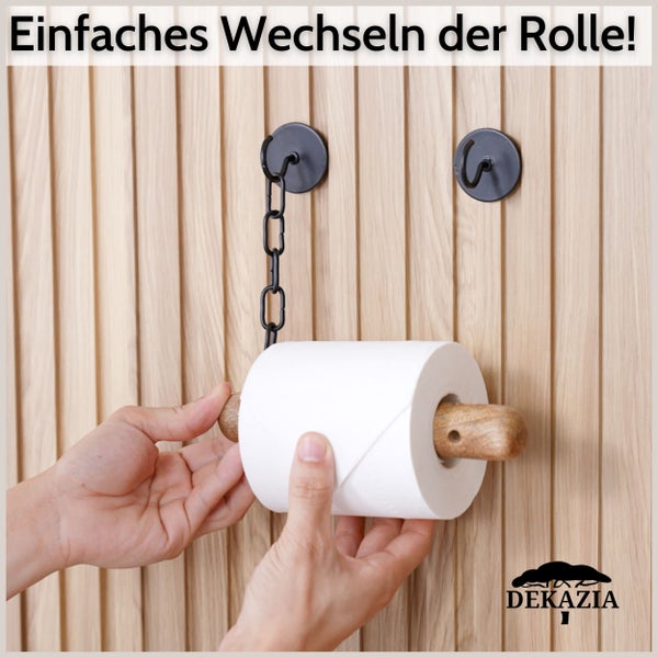 Toilettenpapierhalter aus Holz mit Kette und Wandhaken, eine Person wechselt die Klopapierrolle vor einer Holzwand.