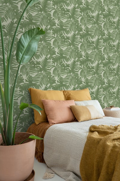 Schlafzimmer mit grüner Blättertapete, Bett und Zimmerpflanze
