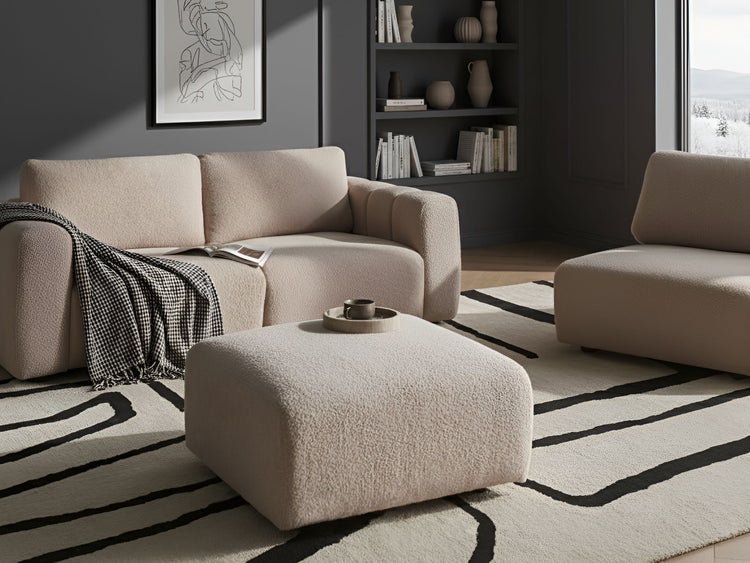 Wohnzimmer mit Sofa, Sessel, Hocker und Teppich