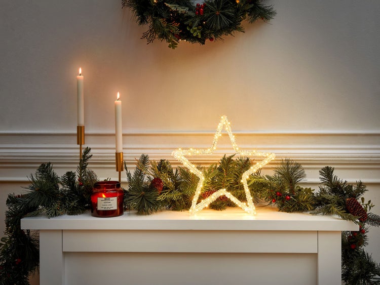 Dekorative Weihnachtsszene mit Stern, Kerzen, Tannengirlande und Kranz für festliche Atmosphäre