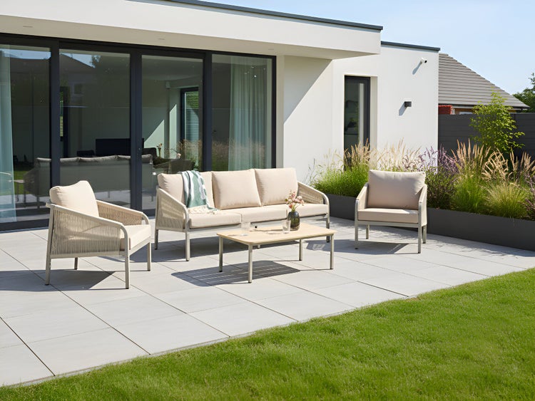 Gartenlounge-Set mit Sofa, Sessel und Tisch auf Terrasse vor Haus
