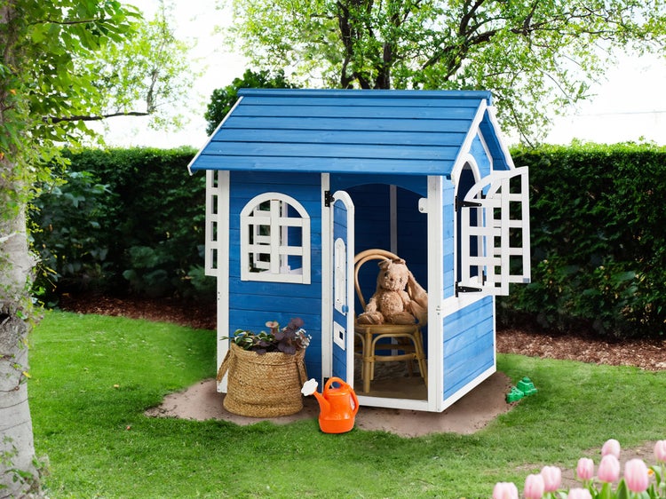 Blaues Kinderspielhaus mit Fenster und Tür im Garten, mit Spielzeug dekoriert.