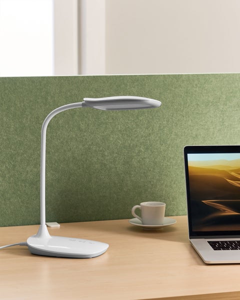 LED-Tischleuchte neben einem Laptop und einer Kaffeetasse auf einem Schreibtisch.