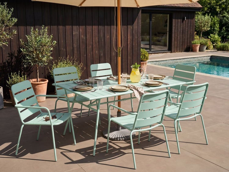 Moderne Gartensitzgruppe aus mintgrünem Metall bestehend aus einem Tisch und sechs Stühlen auf einer Terrasse am Pool.