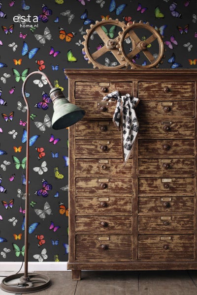 Dekoratives Interieur mit Tapete mit Schmetterlingsmuster, antikem Schrank und Stehlampe