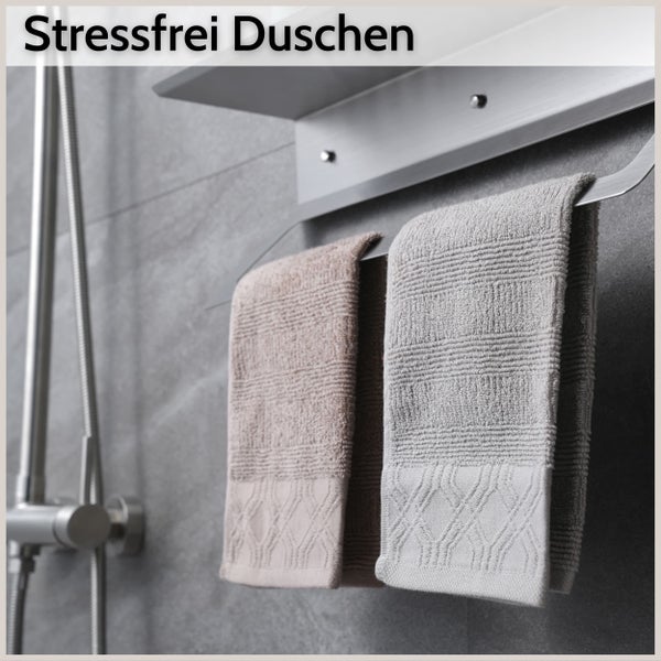 Handtuchhalter mit Ablage und zwei strukturierten Handtüchern an einer gefliesten Wand neben einer Dusche. Text oben: Stressfrei Duschen.
