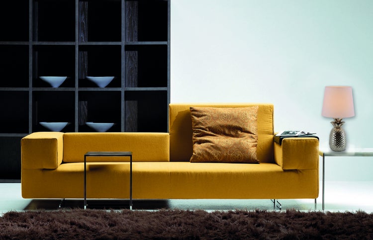 Wohnzimmer mit gelbem Sofa, Dekokissen, Beistelltisch und Regal