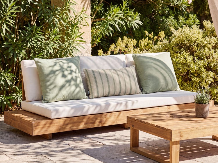 Gartensofa aus Holz mit Polstern und Kissen auf einer Terrasse im Garten stehend
