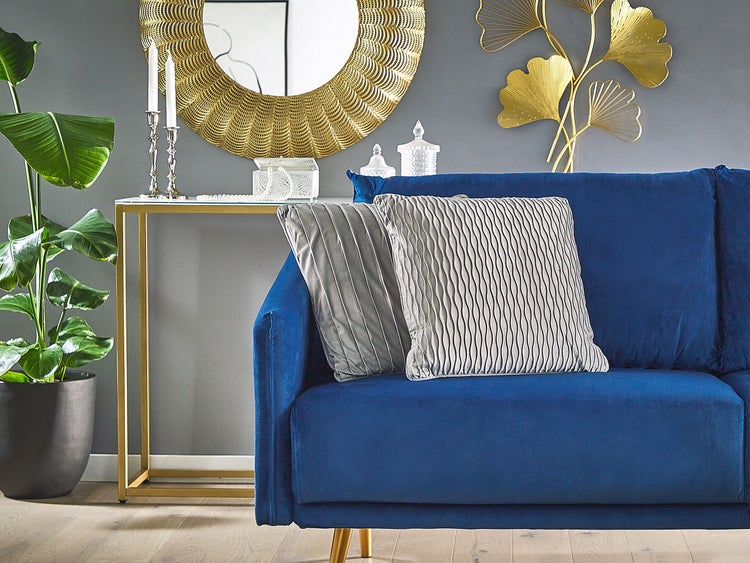 Wohnzimmer mit blauem Sofa, Zierkissen, Tisch und Spiegel