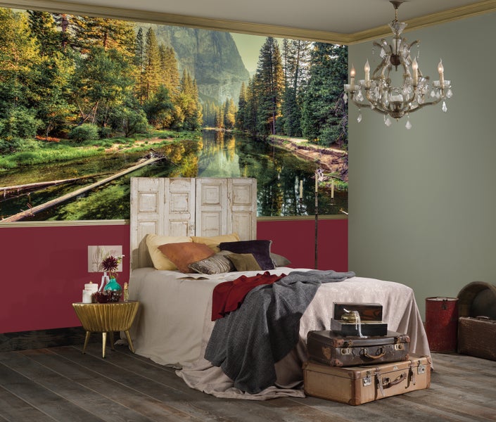 Schlafzimmer mit Wald-Fluss-Fototapete, Bett mit Kopfteil aus Holztüren, dekorativen Koffern und einem Kronleuchter.