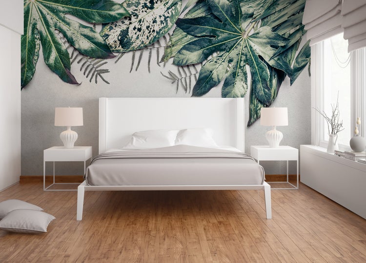 Fototapete mit großen grünen Blättern in einem Schlafzimmer über einem weißen Bett, moderner Stil, heller Holzfußboden.