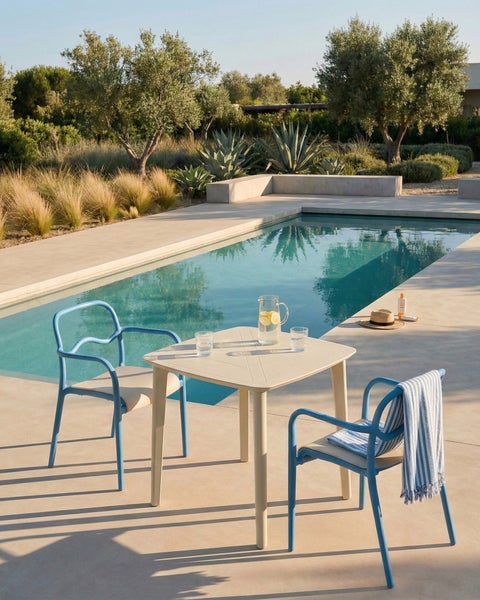 Szene mit Gartentisch, Stühlen und Pool in einem hellen Außenbereich.