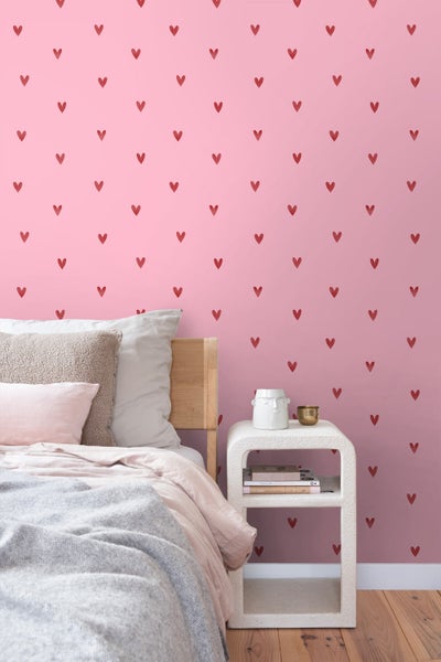 Schlafzimmer mit rosa Tapete und Herzmuster, Bett und Nachttisch