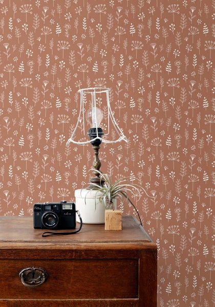 Dekorative Tapete mit Pflanzenmuster in einem Zimmer mit Tisch, Lampe und Kamera