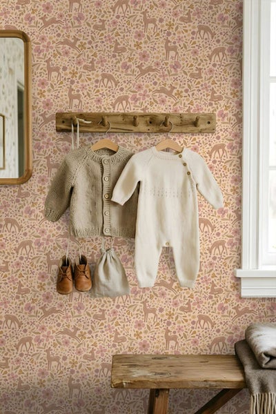 Kindertapete mit Waldmuster, Hirschen und Blumen, montiert in einem gemütlichen Kinderzimmer mit einer Garderobe aus Holz und Babykleidung.