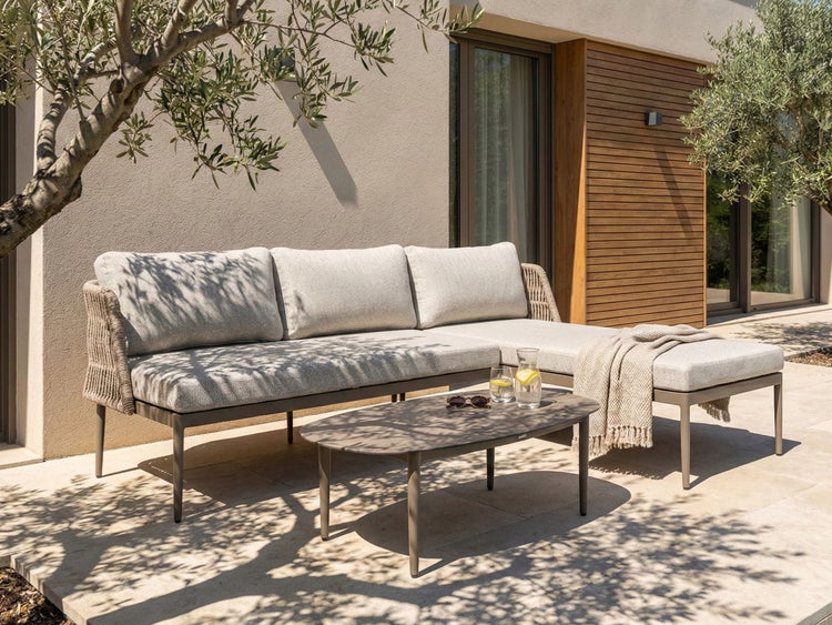 Gartenlounge-Set mit Sofa, Hocker und Tisch auf einer Terrasse