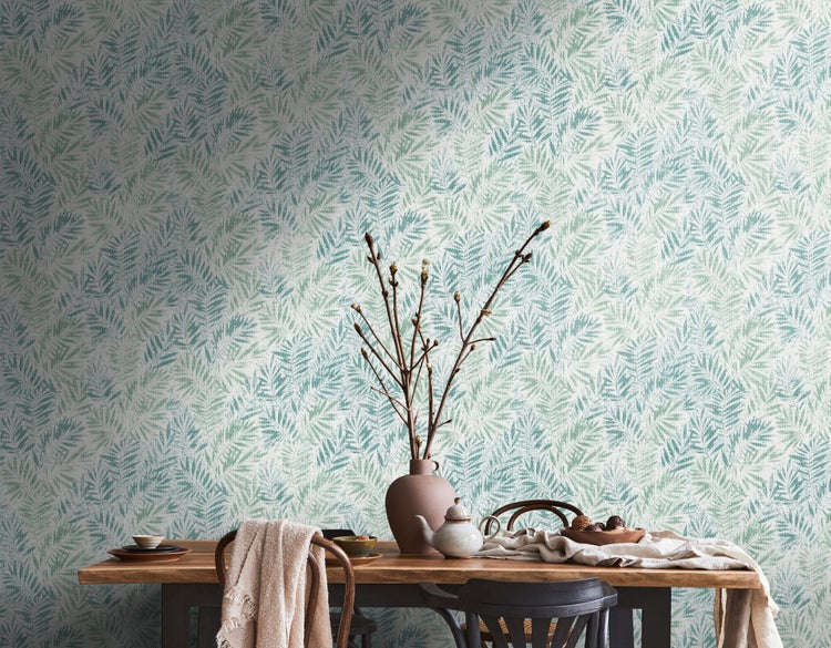 Dekoratives Interieur mit Blattmuster-Tapete, Holztisch und Geschirr.