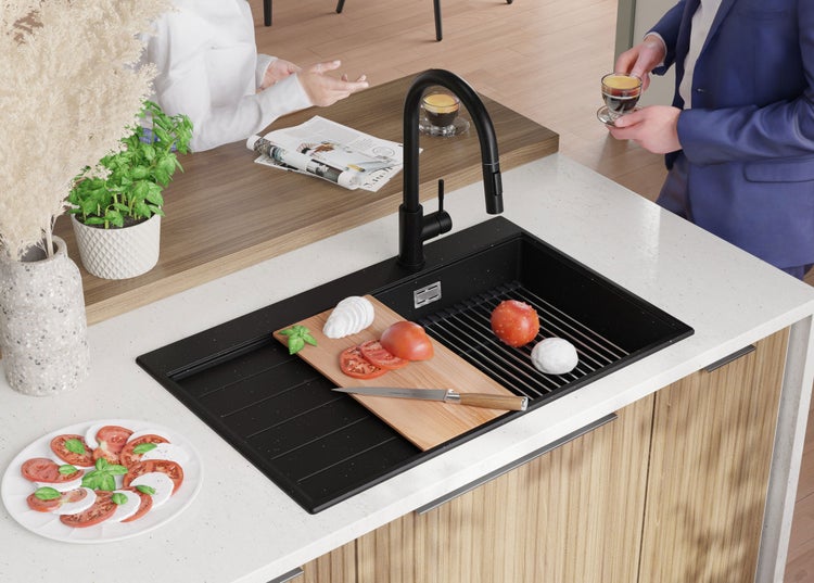 Schwarze Küchenspüle mit Armatur auf einer Küchentheke mit Lebensmitteln