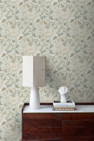 Tapetenmuster mit Blumen und Blättern an einer Wand mit Tisch, Lampe und Dekorationsgegenständen