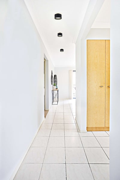 Flur mit Deckenleuchten, Fliesenboden und Holzschrank