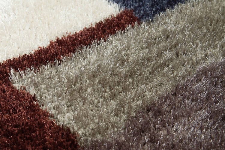 Detailansicht eines weichen Hochflorteppichs mit langen, dichten Fasern in mehreren Farben.