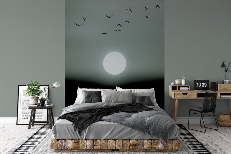 Schlafzimmer mit Wandtapete Motiv Mond und Vögel, Bett mit rustikalem Holzrahmen, Holzschreibtisch und Beistelltisch.