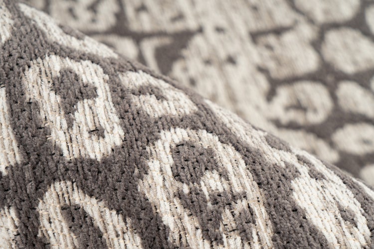 Detailaufnahme eines gemusterten Teppichs mit gewebter Oberfläche.