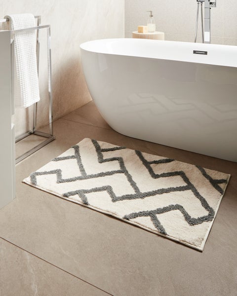 Badezimmer mit Badewanne, Handtuchhalter und Badteppich mit grafischem Muster