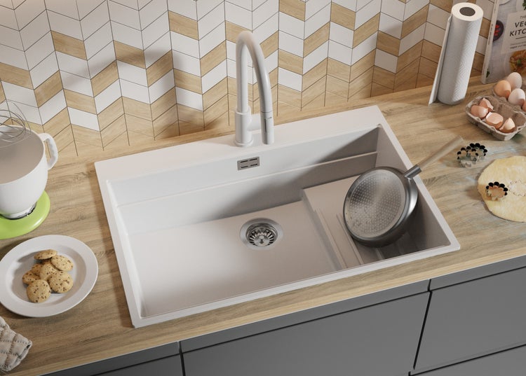 Spüle mit Abtropffläche und Küchenarmatur auf einer Küchentheke mit Essen.