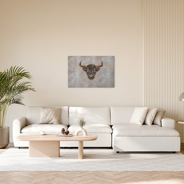 Wohnzimmer mit Sofa, Couchtisch und einem Wandbild mit einem Stierkopf.