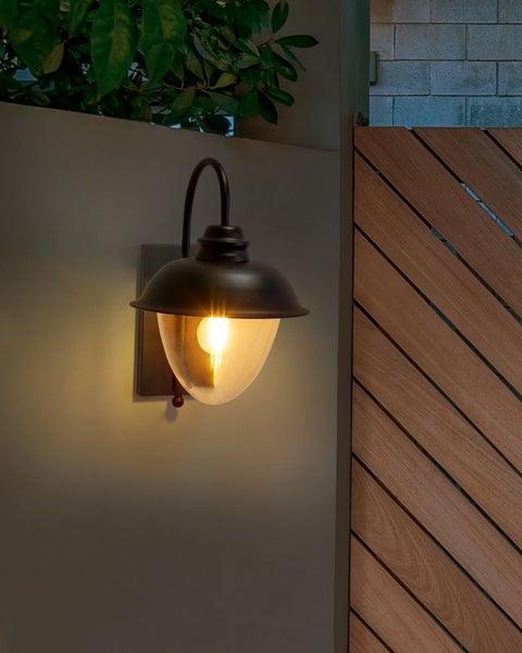 Außenwandleuchte mit gebogener Halterung neben einer Holzwand