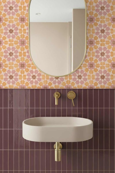 Modernes Badezimmer mit ovalem Waschbecken, Wandarmatur und ovalem Spiegel vor einer Wand mit vertikalen Fliesen und Fliesen mit Sternmuster.