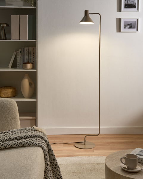 Moderne Stehleuchte aus Metall in einem hellen, organisierten Wohnzimmer neben einem weißen Regal und einem Sessel.
