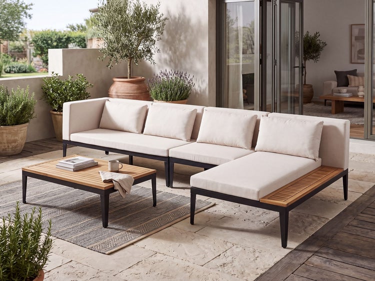 Moderne Loungegarnitur mit Ecksofa und Couchtisch aus Metall und Holz auf einer Terrasse mit Pflanzen.
