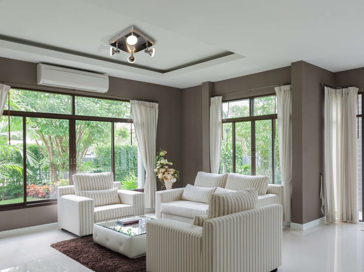 Wohnzimmer mit Sofas, Sessel, Fenstern, Klimaanlage und Deckenleuchte